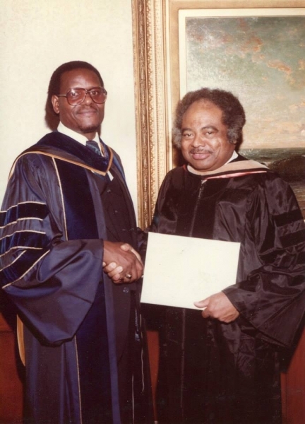 University officer shaking hands with an honouree holding a diploma folder