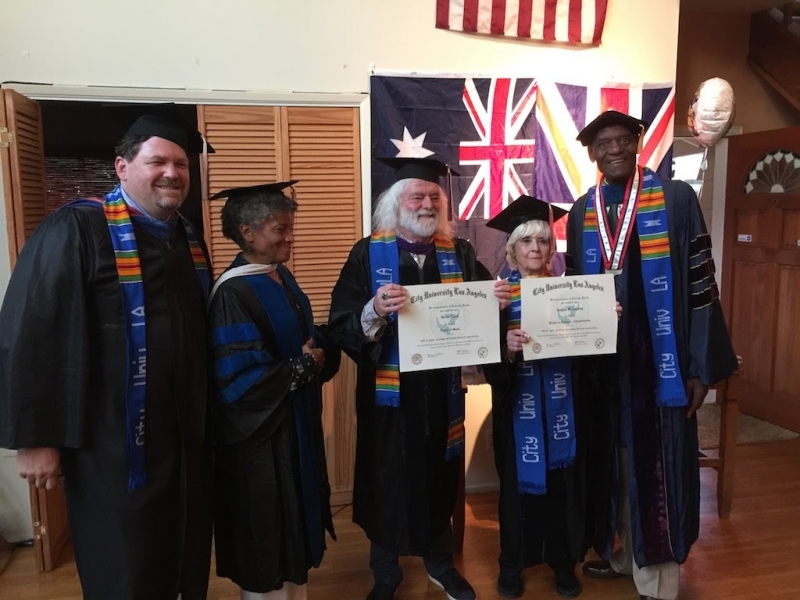 Two honorary degree recipients holding their City University Los Angeles certificates with faculty