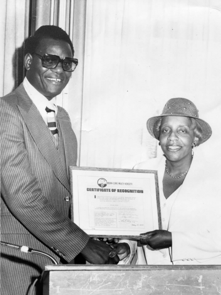 Two people holding a framed Certificate of Recognition at a podium