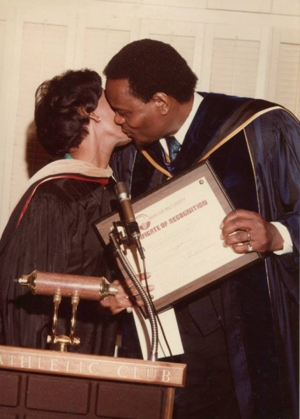 Honouree greeted at the podium while holding a framed Certificate of Recognition